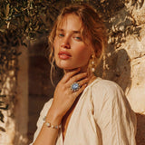 Pulsera con cuentas de cuarzo nublado, perlas de agua dulce y perla barroca central envuelta en oro, sobre fondo blanco.